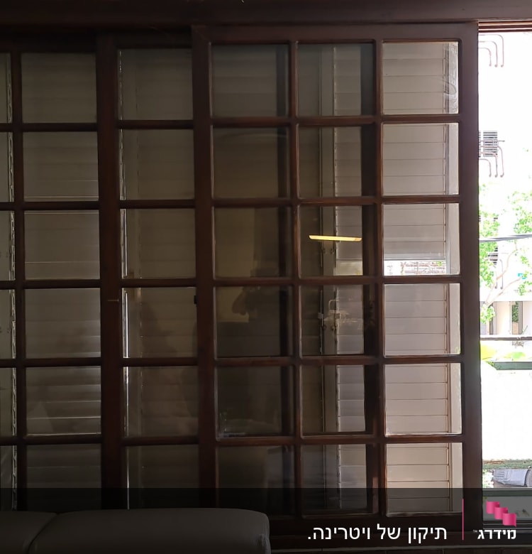 חלון אלומיניום עם תריסים סגורים ומסגרת עץ